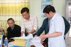 Le vice-ministre de l'Agriculture et du Développement rural, Phung Duc Tiên (premier à gauche), et les inspecteurs examinent les registres quotidiens des bateaux de pêche au port de pêche de Dông Tac, dans la ville de Tuy Hoa, province de Phu Yên. Photo : VNA