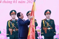 Le Premier ministre Pham Minh Chinh épingle l'insigne "Héros des forces armées populaires" sur le drapeau traditionnel des forces armées de Hô Chi Minh-Ville. Photo: VNA