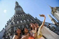 Un groupe de touristes vietnamiens en costumes traditionnels thaïlandais prennent des photos devant le temple Wat Arun, à Bangkok, en Thaïlande. Photo : Reuters