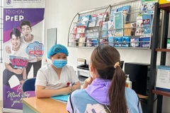 Une agente de santé informe un citoyen sur le VIH/SIDA. Photo : VietnamPlus