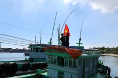 Le poste de garde-frontière de Son Trà (commandement des garde-frontières de la ville de Dà Nang) présente le drapeau national aux bateaux de pêche. Photo : VNA