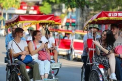 Des touristes étrangers prennent un cyclo-pousse pour découvrir le Vieux quartier de Hanoi. Photo : VNA