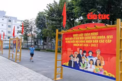 Un homme faisant de la gymnastique passe près ds banderoles et des slogans sur les élections législatives affichés dans les zones résidentielles et les espaces publics du quartier de Thông Tây Hôi, à Hô Chi Minh-Ville. Photo : Journal "Tin tuc và Dân tôc"