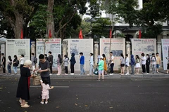 Une file de visiteurs faisant la queue pour découvrir l’exposition photographique « Éclat du nom de l’Oncle » et recevoir le supplément spécial du Journal Nhân Dân, à l’occasion du 135e anniversaire de la naissance du président Hô Chi Minh. Photo : NDEL