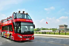 Des touristes étrangers admirent le paysage du mausolée d'Hô Chi Minh et de la place Ba Dinh depuis un bus à impériale. Photo : VNP