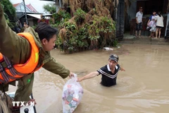 Des agents de la sécurité publique de la province de Dak Lak distribuent des vivres aux habitants des zones fortement inondées le long de la rivière Banh Lai. Photo : VNA