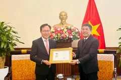 Le vice-ministre permanent des Affaires étrangères Nguyên Minh Vu (à droite) remet l’insigne «Pour la cause des affaires étrangères du Vietnam» au directeur général de Samsung Vietnam, Choi Joo Ho, à Hanoi, le 13 février. Photo : VNA