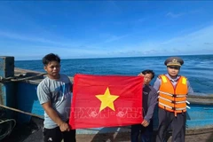 Deux pêcheurs exhibent le drapeau rouge à étoile jaune. Photo: VNA