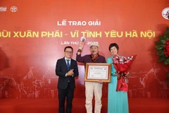 Lê Quôc Minh (à gauche), membre du Comité central du Parti, chef adjoint de la Commission de la sensibilisation, de l'éducation et de la mobilisation de masse du Comité central du Parti et président de l'Association des journalistes vietnamiens, et Vu Viêt Trang (à droite), directrice générale de l'Agence vietnamienne d’information, remettent le Grand prix au musicien Trân Tiên. Photo : VNA