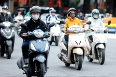 Des gens se déplacent pour se rendre au travail par une journée froide à Hanoi. Photo : VNA