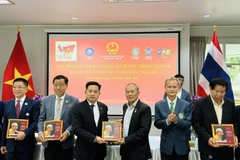 Des ressortissants vietnamiens reçoivent une copie du livre bilingue "L'Oncle Hô en Thaïland". Photo: VNA