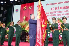 Le secrétaire général du Parti Tô Lâm épingle l’insigne de Héros des Forces armées populaires sur le drapeau traditionnel du Département général de l’industrie de la défense. Photo : VNA