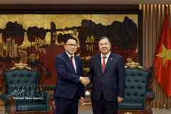Le vice-Premier ministre permanent Pham Gia Tuc (à droite) serre la main du ministre lao de l’Agriculture et de l’Environnement, Linkham Douangsavanh, à Hanoi, le 14 juillet. Photo : VNA