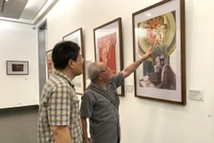 Le peintre Trân Duy Truc (droite) présente son œuvre à l’exposition.