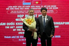 Le président de l'Association d'amitié Vietnam - Singapour (gauche) offre un bouquet de fleurs au consul général de Singapour à Hô Chi Minh-Ville, Pang Te Cheng. Photo: sggp