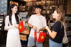 Fin avril, des drapeaux rouges à étoiles jaunes sont offerts à des touristes américains lors de leur visite à Hô Chi Minh-Ville. Photo : Vietnam+