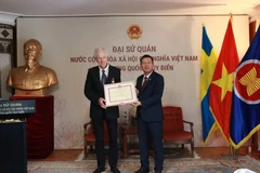 L’ambassadeur du Vietnam en Suède, Trân Van Tuân (droite), remet l’insigne « Pour la cause de la Culture, des Sports et du Tourisme » au réalisateur suédois Bo Öhlén. Photo: VNA