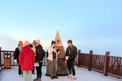 Les touristes sont ravis de découvrir la glace au sommet du mont Fansipan. Photo : VNA