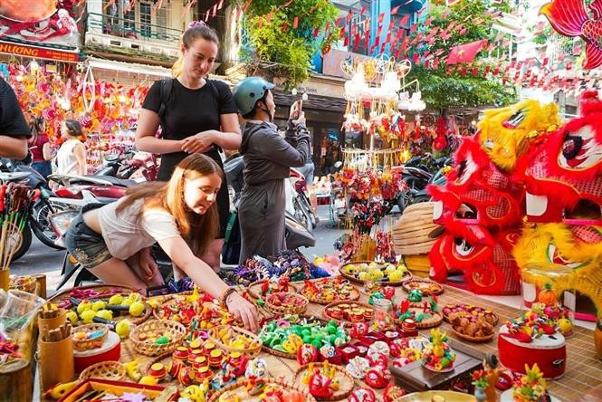 Les touristes étrangers aiment en savoir davantage sur les jouets traditionnels vietnamiens de la Fête de la mi-automne.. Photo : VNA