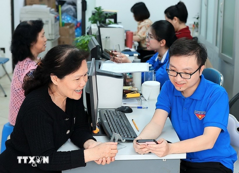 Des jeunes volontaires de Hàng Bồ (Hanoï) aident les habitants dans les démarches administratives en ligne. Photo : VNA