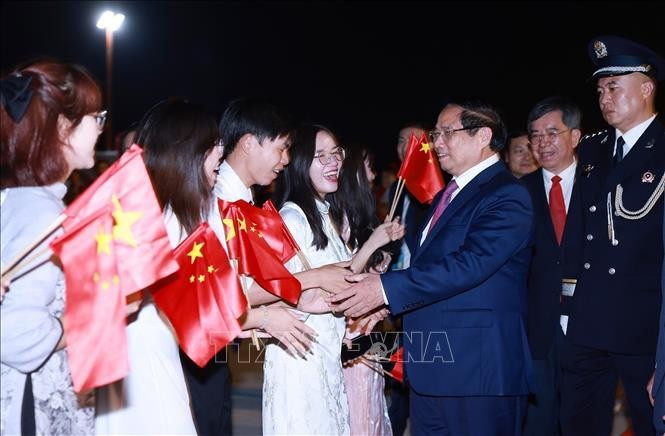 Le Premier ministre Pham Minh Chinh est accueilli à l'aéroport par des représentants de la communauté vietnamienne en Chine. Photo : VNA