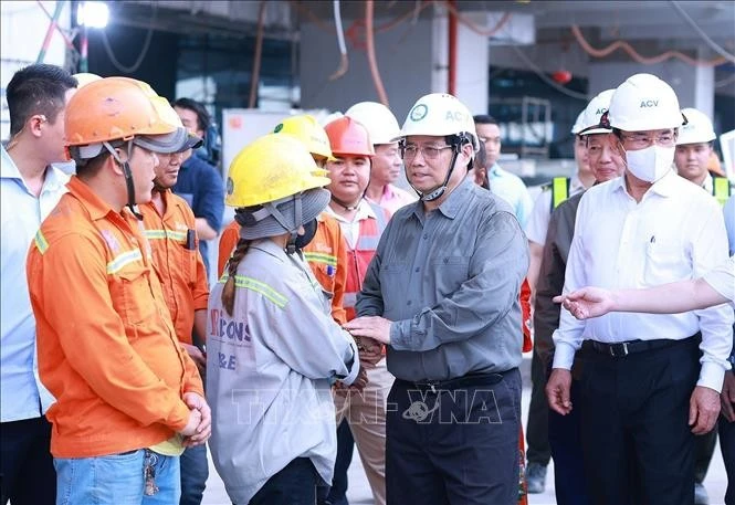 Le Premier ministre Pham Minh Chinh (deuxième à partir de la droite) adresse ses vœux de Nouvel An aux ouvriers du chantier de construction du Terminal 3 de l'aéroport international Tan Son Nhat à Ho Chi Minh-Ville. (Photo : VNA) 