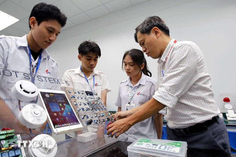 Des professeurs de la faculté de technologie électronique de l'université industrielle de Hô Chi Minh-Ville encadrent les étudiants dans leurs études et leurs recherches au laboratoire IoT et IA. Photo : VNA