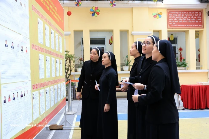 Des religieuses de la Congrégation des Amantes de la Sainte-Croix, au 31 rue Nhà Chung, consultent la liste des candidats au bureau de vote n°1, dans le quartier de Hoàn Kiem. Photo : VNA