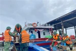 Des gardes-frontières aident des pêcheurs à consolider et à amarrer leurs bateaux. Photo : VNA