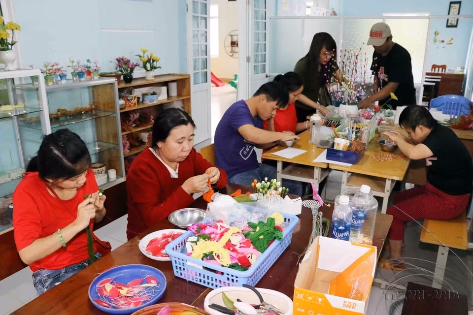 Des victimes de l'agent orange apprennent la confection de fleurs en mousseline au centre n°3 de l'Association des victimes de l'agent orange/dioxine de Da Nang. Photo: VNA