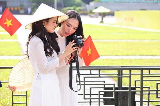 De jeunes femmes revêtent l'ao dai, la tenue traditionnelle vietnamienne, pour célébrer le 80e anniversaire de la Révolution d'août et de la Fête nationale. Photo : VNA check-in-2.jpg