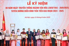 Le secrétaire général Tô Lâm et le ministre de la Culture, des Sports et du Tourisme Nguyên Van Hùng remettent des certificats de mérite et des fleurs pour féliciter les figures exemplaires du secteur culturel. Photo : VNA