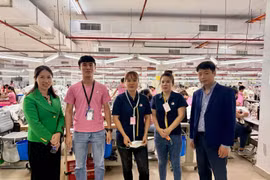 Le Ngoc Toan, premier secrétaire et chef du Comité de gestion des travailleurs et experts en Malaisie (premier à droite), Thai Thi Huong, première secrétaire de l'ambassade du Vietnam en Malaisie (premier à gauche), prennent une photo avec des travailleurs vietnamiens à l'usine Ramatex Textiles. Photo: VNA