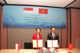 Le ministre vietnamien de l'Industrie et du Commerce, Nguyên Hông Diên (à droite), et la ministre singapourienne du Développement durable et de l'Environnement, également chargée des Relations commerciales, Grace Fu. échangent le protocole d'accord de coopération. Photo: VNA