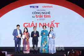 La directrice générale de l'Agence vietnamienne d'information (VNA), Vu Viet Trang, et le président de l'Association des journalistes vietnamiens (VNA), Le Quoc Minh, ont remis le premier prix aux lauréats lors de la cérémonie et de l'exposition "Technologie avec le cœur" 2024. Photo : VNA