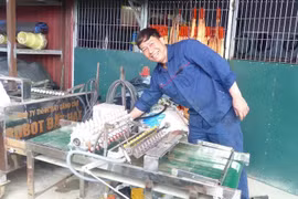 Pham Van Hat pose aux côtés de son célèbre produit, le "robot semeur". Photo: sggp.org.vn