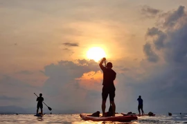 Les touristes pratiquant le SUP (Stand-Up Paddle) pour surfer sur les douces vagues ondulées de l'océan à Binh Son (ville de Phan Rang - Thap Cham) et admirer le lever du soleil. Photo : VNA