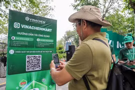 Les gens scannent directement le code QR de la plateforme de commerce électronique VinachemMart dans la rue piétonne du lac Hoàn Kiêm. Photo: VNA