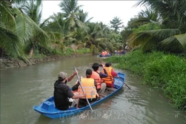 Des touristes font l'expérience du canoë sur la rivière à la ferme touristique de chèvres de Dong Nghi, à Tiên Giang. Photo: VNA