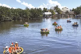 De nombreux touristes font des excursions en bateau autour du village de palmiers à nipa de Cẩm Thanh pour découvrir l'un des plus beaux villages du monde. Photo : VNA