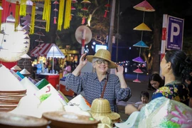Un touriste étranger apprécie les produits traditionnels vietnamiens lors de sa découverte d'Hanoï (Photo : VNA)