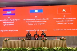 Les ministres de la Défense du Vietnam, du Laos et du Cambodge signent le compte rendu de leur réunion annuelle à Vientiane, le 15 octobre. (Photo : VNA)