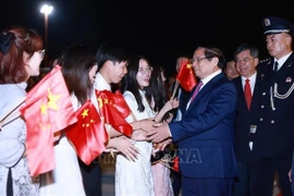 Le Premier ministre Pham Minh Chinh est accueilli à l'aéroport par des représentants de la communauté vietnamienne en Chine. Photo : VNA