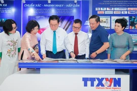 Nguyen Trong Nghia (troisième à partir de la gauche), membre du Politburo et président de la Commission de l'information, de l'éducation et de la mobilisation de masse du Comité central du Parti, visite le stand de l'Agence vietnamienne d'Informaton. (Photo : VNA)