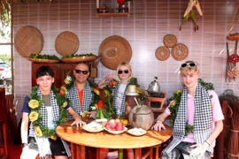 Des touristes prennent des photos dans l’espace « Bếp xưa », recréant la cuisine traditionnelle des habitants du Sud du Vietnam. Photo : VNA