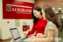 Des employés de la Banque vietnamienne de l’Agriculture et du Développement rural (Agribank) guident les clients dans la réalisation de transactions sécurisées sur les canaux numériques. Photo : Journal Quân đội nhân dân