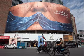 Des automobilistes passent devant un panneau d'affichage anti-américain faisant référence au président Donald Trump et au détroit d'Ormuz, place Valiasr à Téhéran, le 2 mai 2026. (Photo : AFP)