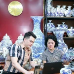 L’artisan Trân Trung Hiêu, dans la commune de Bat Tràng, district de Gia Lâm, à Hanoi, partage avec sa collègue sur la manière d’introduire des céramiques sur les plateformes de commerce électronique. Photo : NDEL