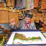  Un artisan brode une peinture dans l'espace d'exposition. Photo : VNA