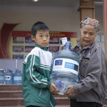 Dans la province de Thai Nguyên, dévastée par le typhon, une femme et son petit-enfant rapportent chez eux une bouteille d'eau potable fournie grâce au soutien de l'UE et de l'UNICEF. Photo : UNICEF Vietnam